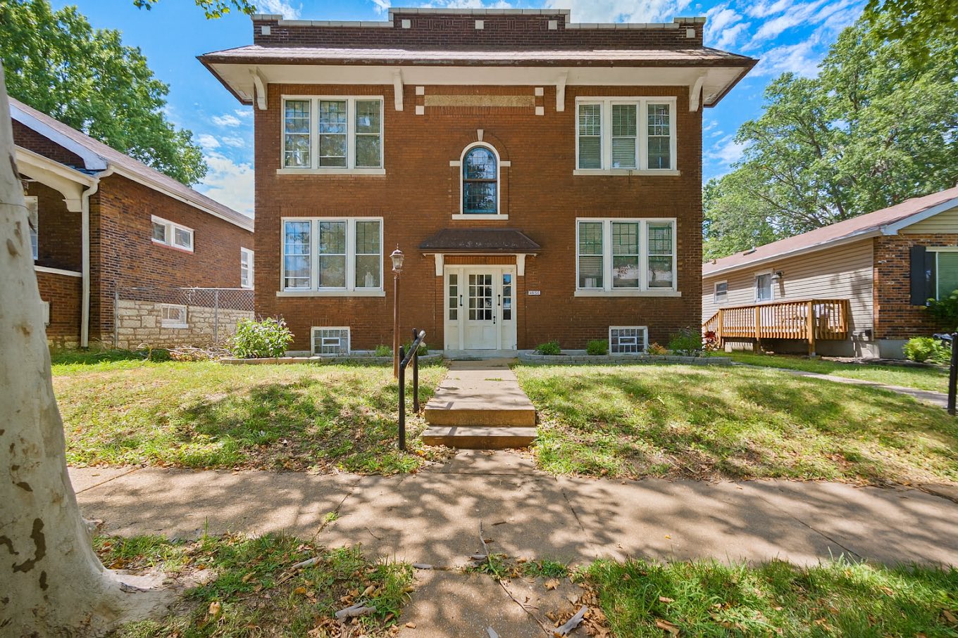 Red-brick St. Louis four-family building on a tree-lined city street